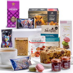 Contents of a luxury afternoon tea gift hamper featuring a tea, fudge, shortbread, jams, popcorn, nuts, macarons, cake