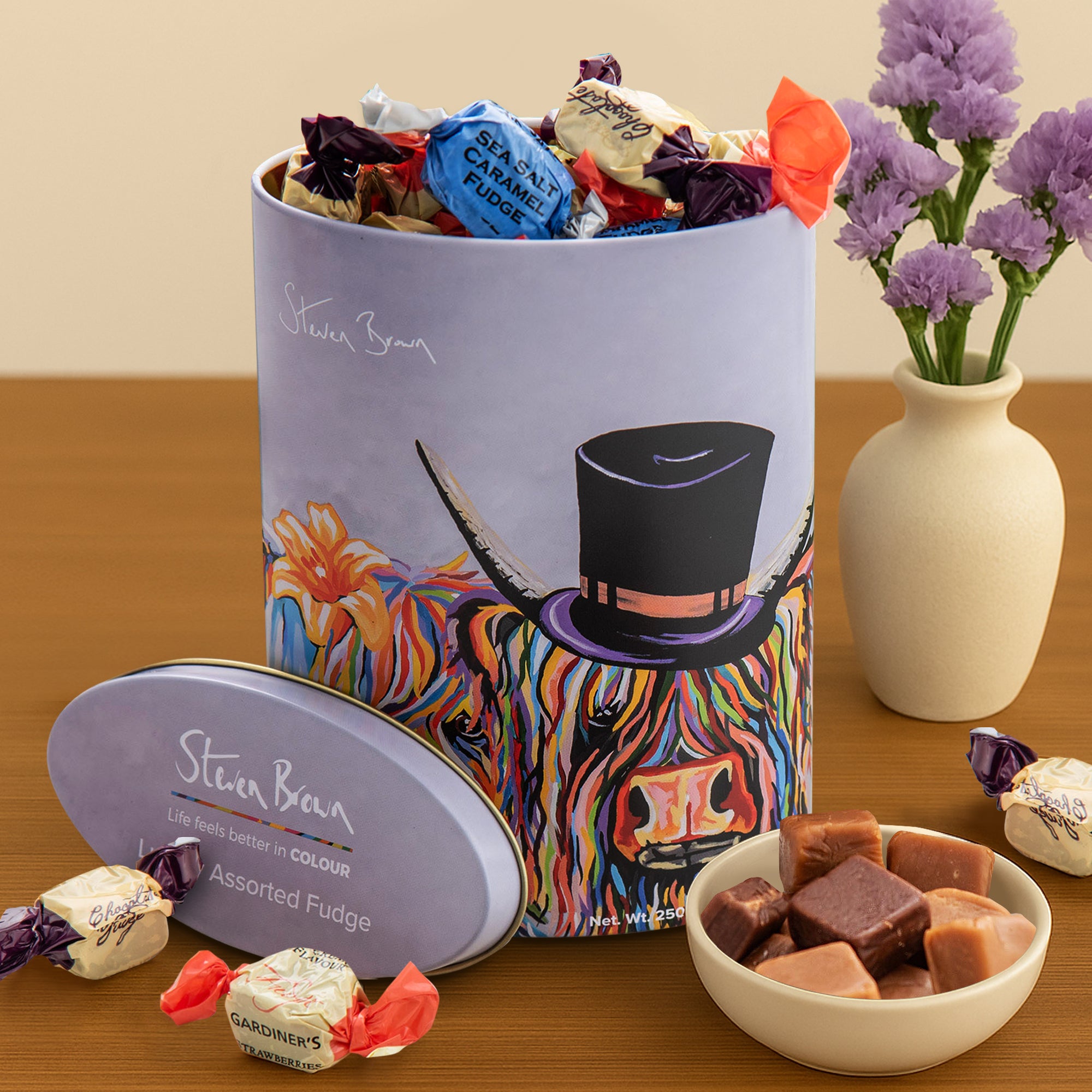 Gardiners of Scotland McHappily Couple Assorted Fudge tin featuring Steven Brown’s joyful Highland cow couple artwork—filled with a selection of traditional Scottish fudge flavours
